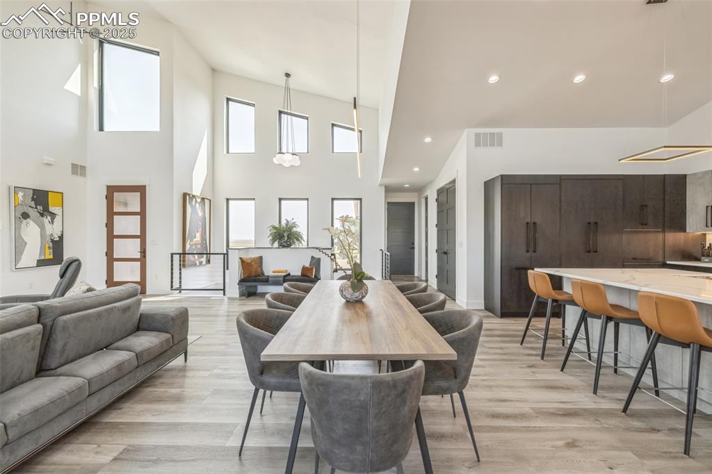 Image 11 of 50: Dining space featuring light wood-style flooring, a towering ceiling, and r