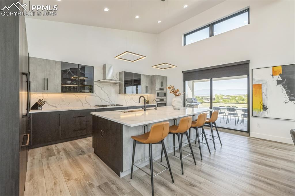 Image 12 of 50: Kitchen featuring modern cabinets, a kitchen breakfast bar, decorative back