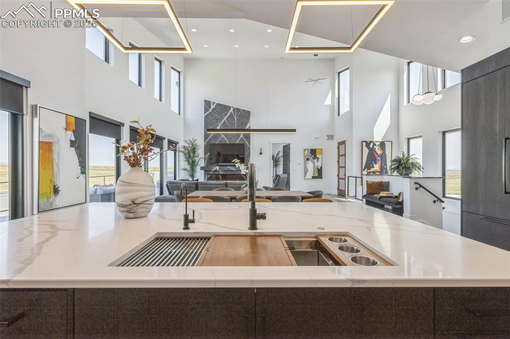 Image 16 of 50: Kitchen featuring open floor plan, an island with sink, light stone counter