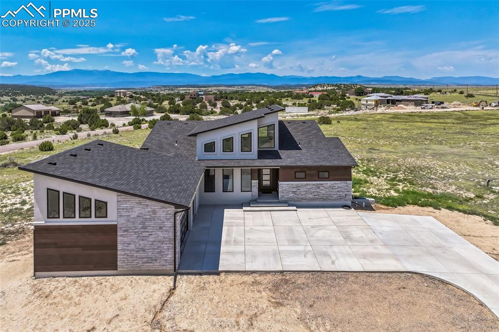 Image 2 of 50: View of front of house featuring stone siding, a mountain view, a residenti