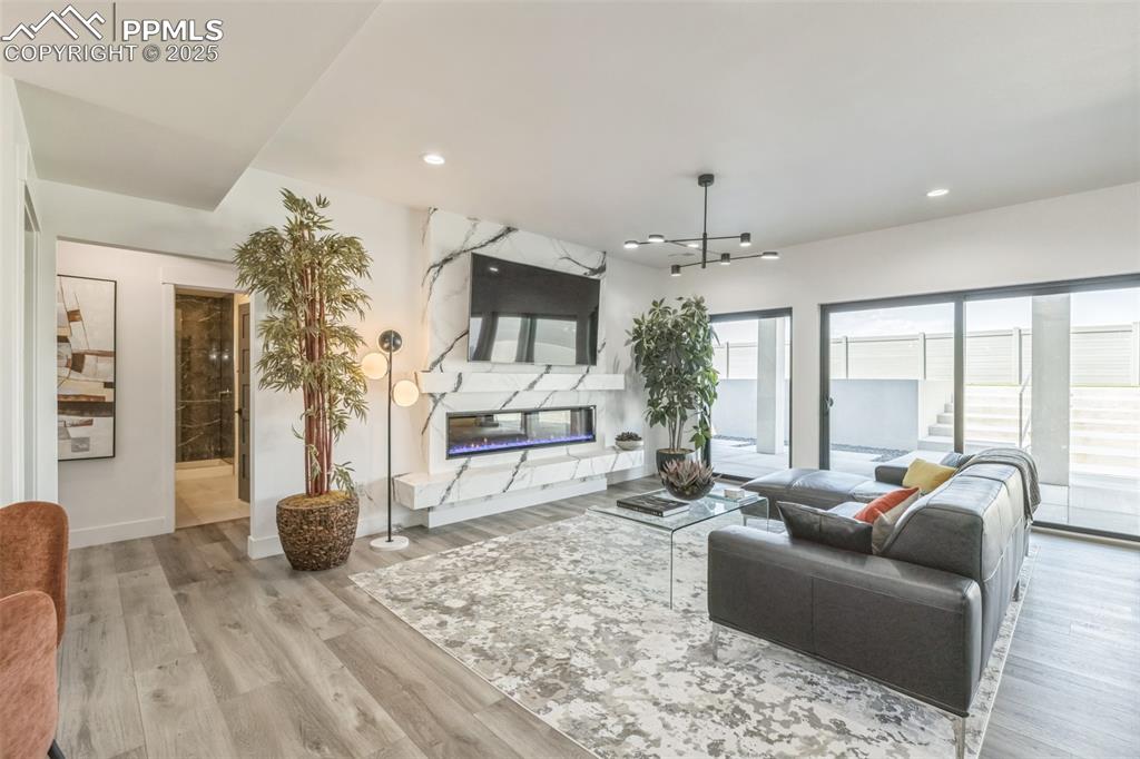 Image 21 of 50: Living room with a fireplace, wood finished floors, and recessed lighting