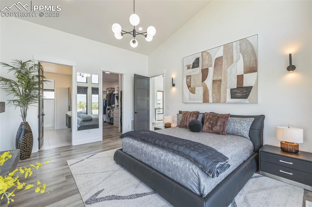 Image 23 of 50: Bedroom with a spacious closet, wood finished floors, vaulted ceiling, a ch