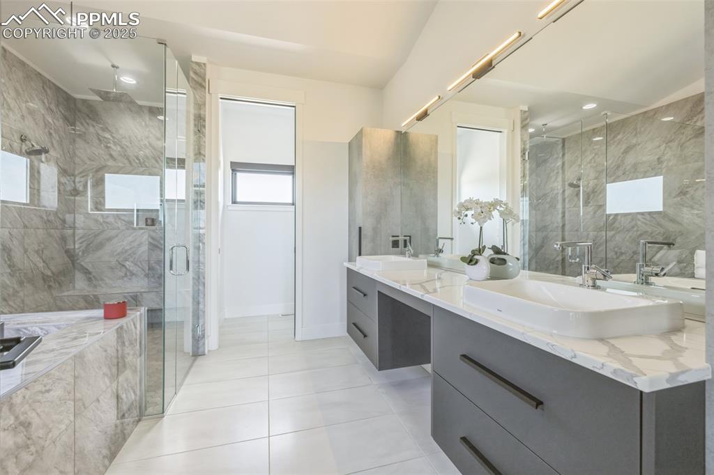 Image 26 of 50: Bathroom with double vanity, a stall shower, tile patterned flooring, and r