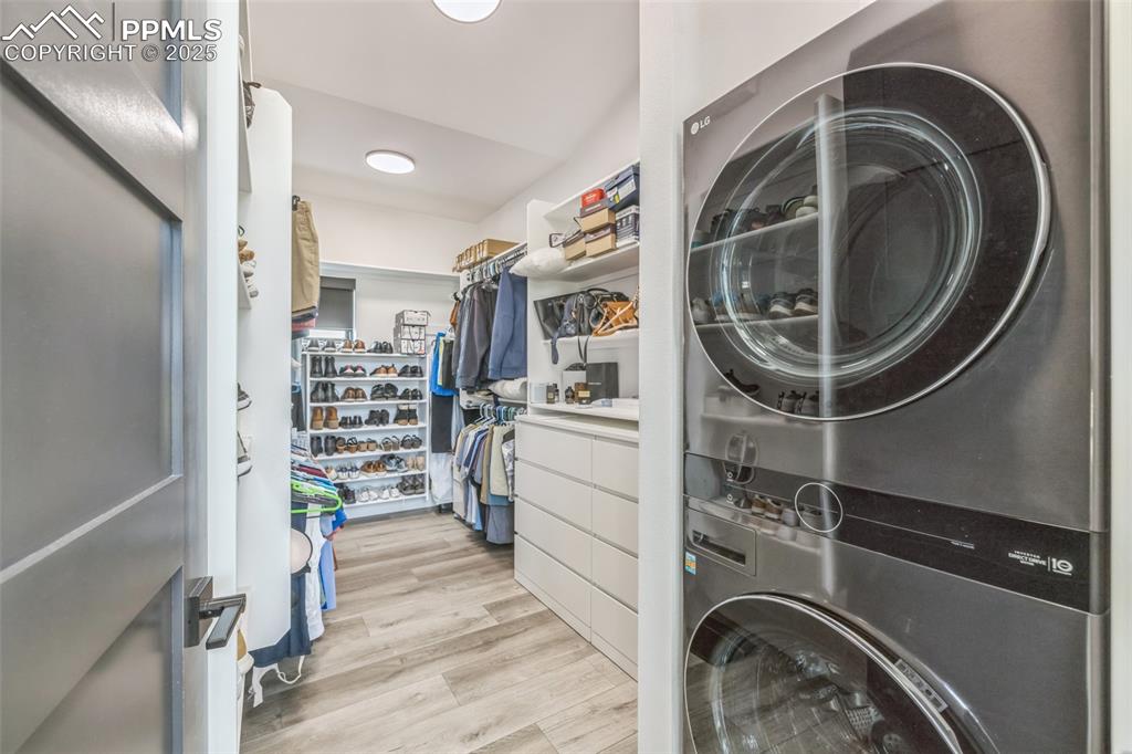 Image 31 of 50: Washroom featuring stacked washer / drying machine and light wood-style flo