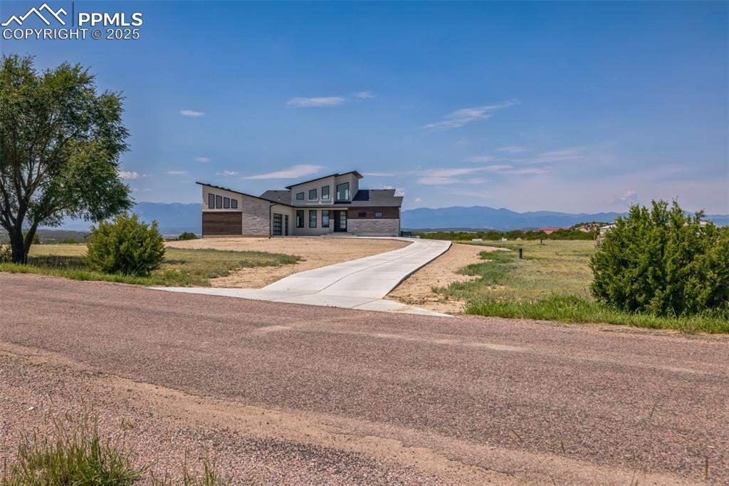 Image 46 of 50: View of front of property featuring stone siding, a mountain view, and driv