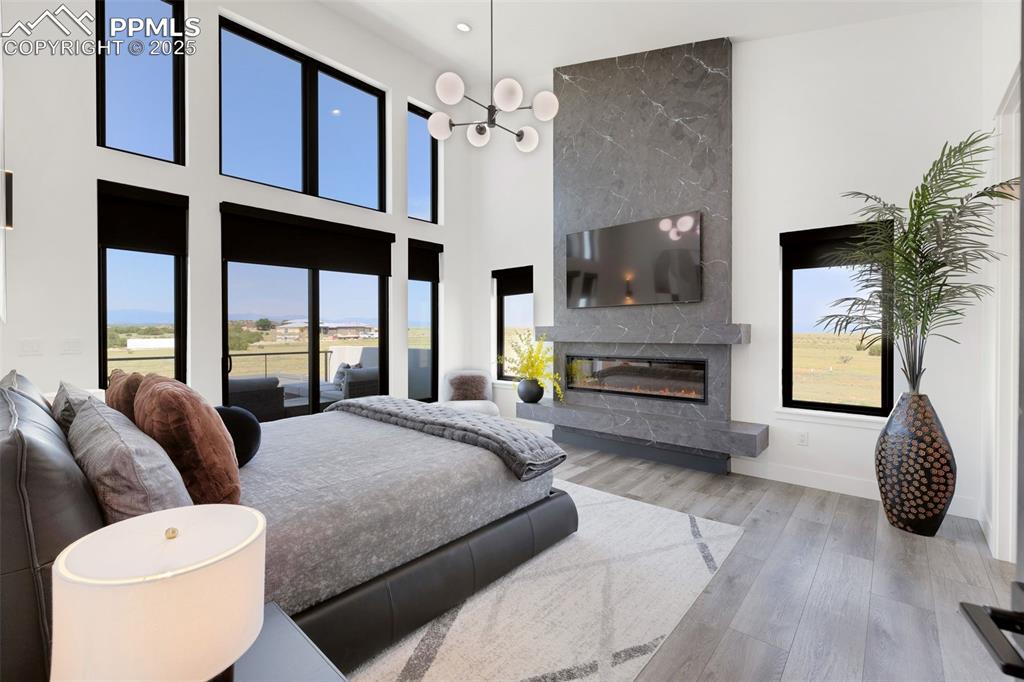 Image 8 of 50: Bedroom featuring a fireplace, wood finished floors, multiple windows, a to