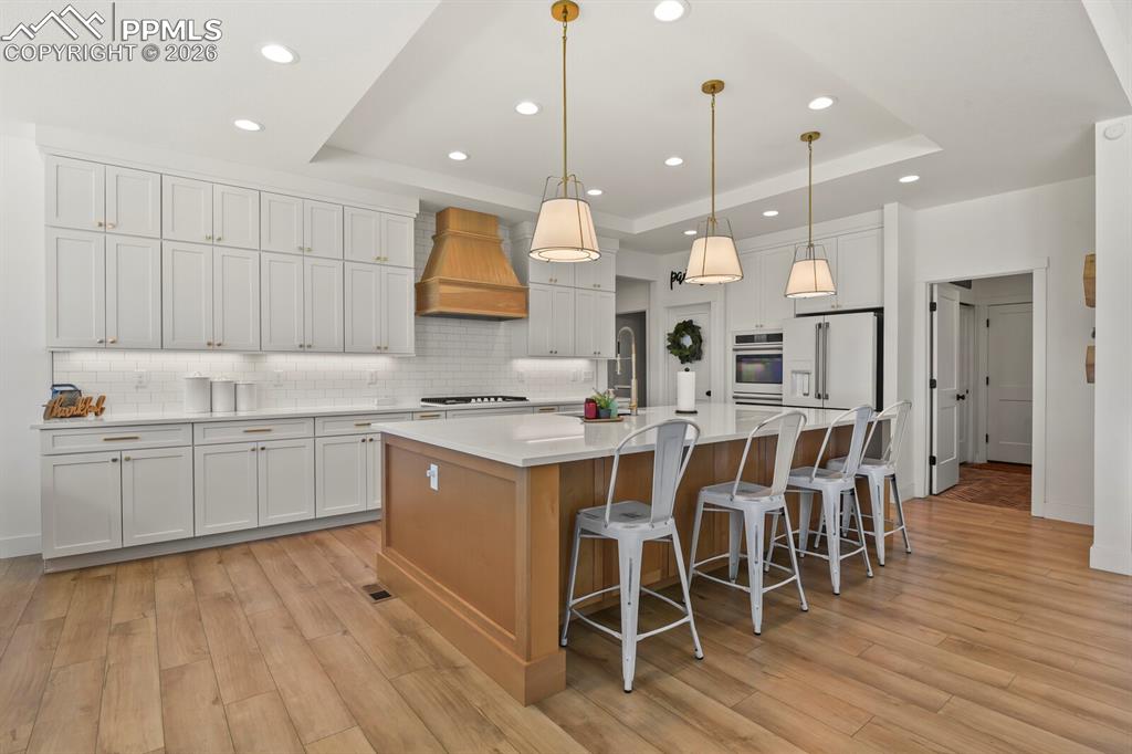 Image 10 of 47: Kitchen featuring a tray ceiling, a large island with sink, a breakfast bar