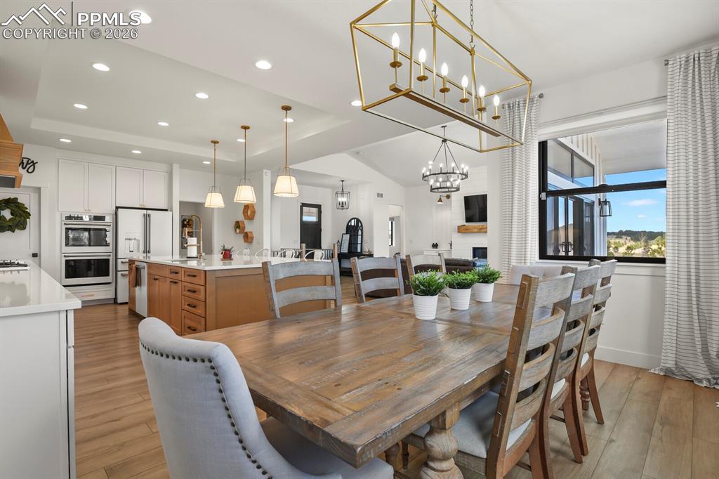 Image 15 of 47: Dining space featuring a tray ceiling, light wood-style flooring, suspended