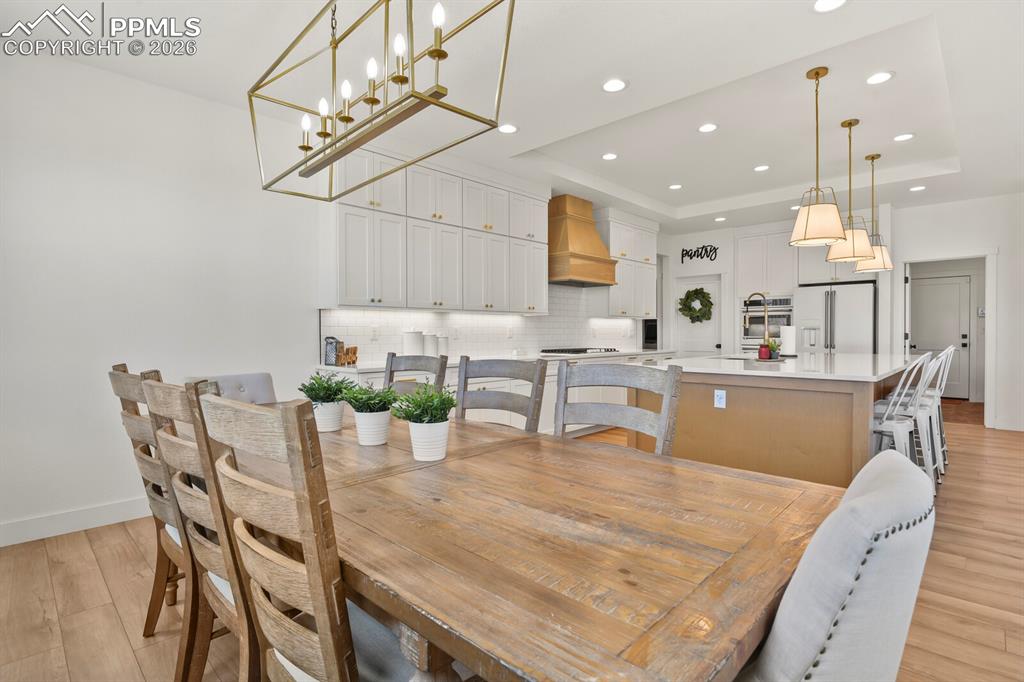 Image 16 of 47: Dining room featuring light wood-type flooring, a tray ceiling, and recesse