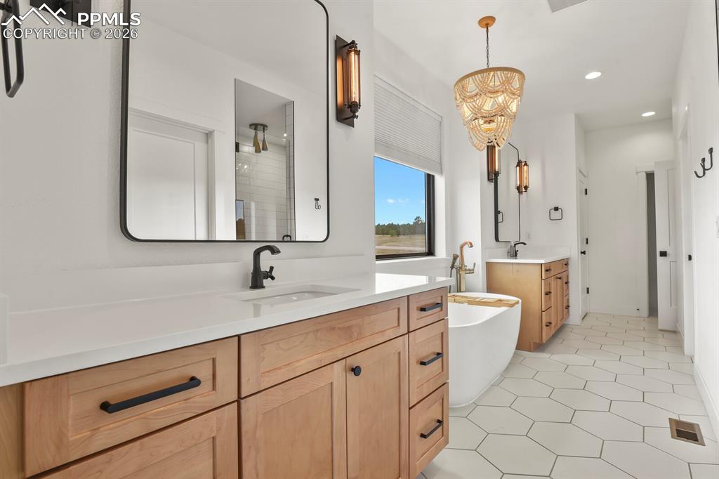 Image 22 of 47: Bathroom featuring two vanities, a freestanding tub, recessed lighting, and