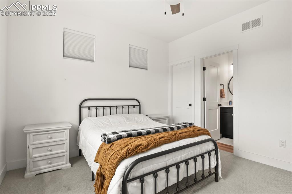 Image 25 of 47: Bedroom featuring light carpet, ceiling fan, and ensuite bath