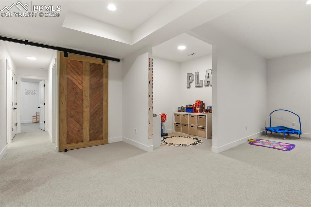 Image 31 of 47: Game room with a barn door, light colored carpet, and recessed lighting