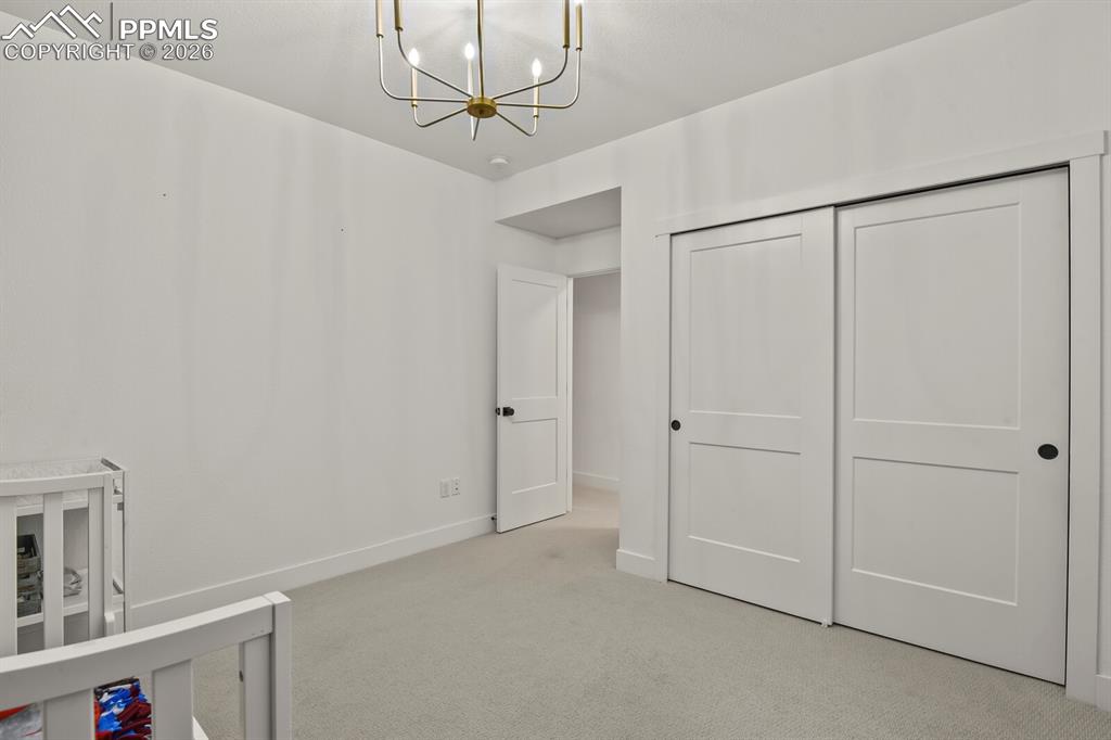 Image 34 of 47: Unfurnished bedroom featuring suspended lighting, light colored carpet, and