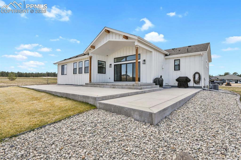 Image 38 of 47: Back of property featuring board and batten siding and a patio