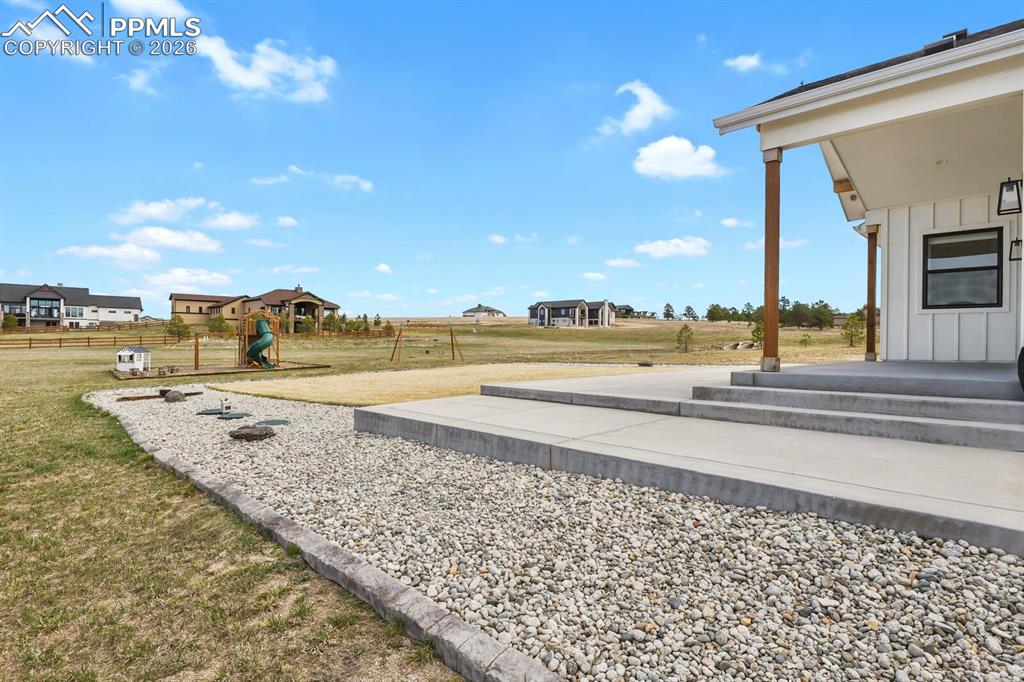 Image 39 of 47: View of green lawn with a patio and a playground