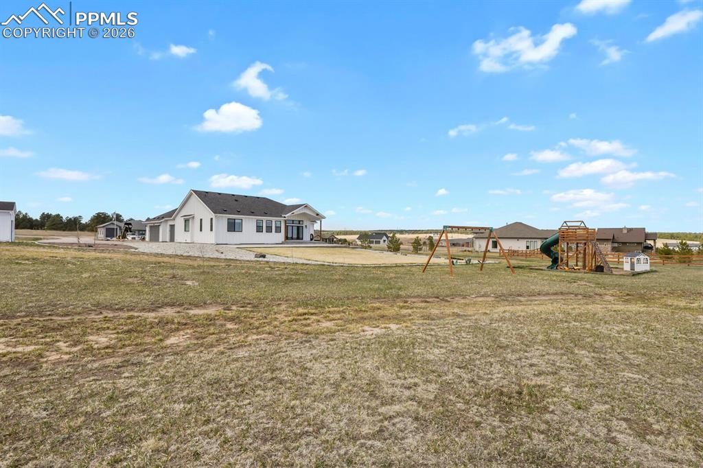 Image 42 of 47: View of grassy yard featuring a playground
