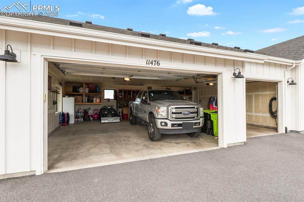 Image 44 of 47: Garage with freestanding refrigerator and driveway