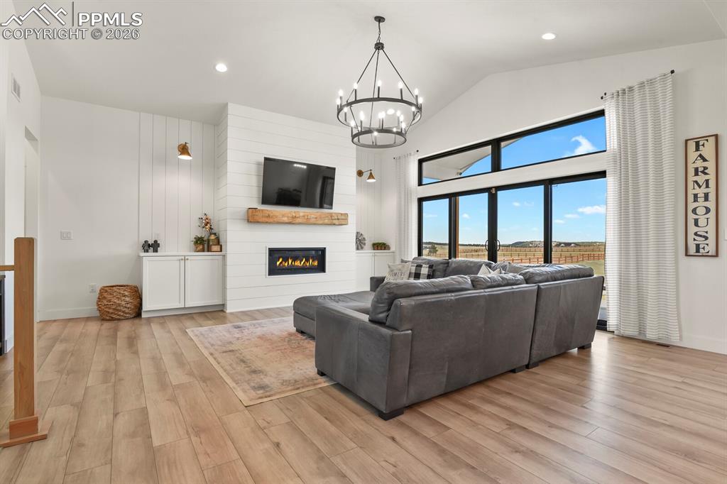 Image 5 of 47: Living area featuring a large fireplace, light wood-style flooring, a chand