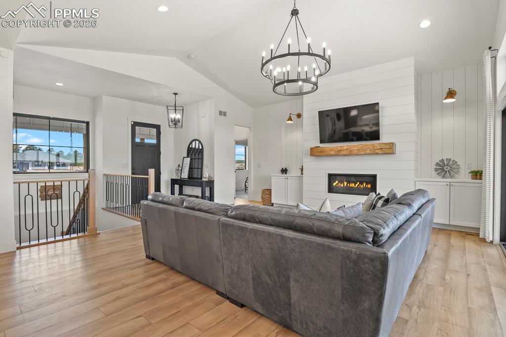 Image 6 of 47: Living area featuring a chandelier, light wood-style flooring, and a firepl