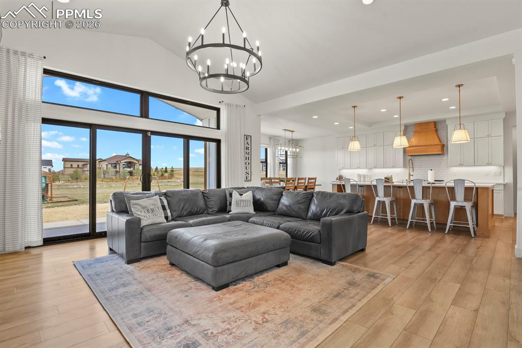 Image 8 of 47: Living room featuring hanging lights, lofted ceiling, and light wood-style 