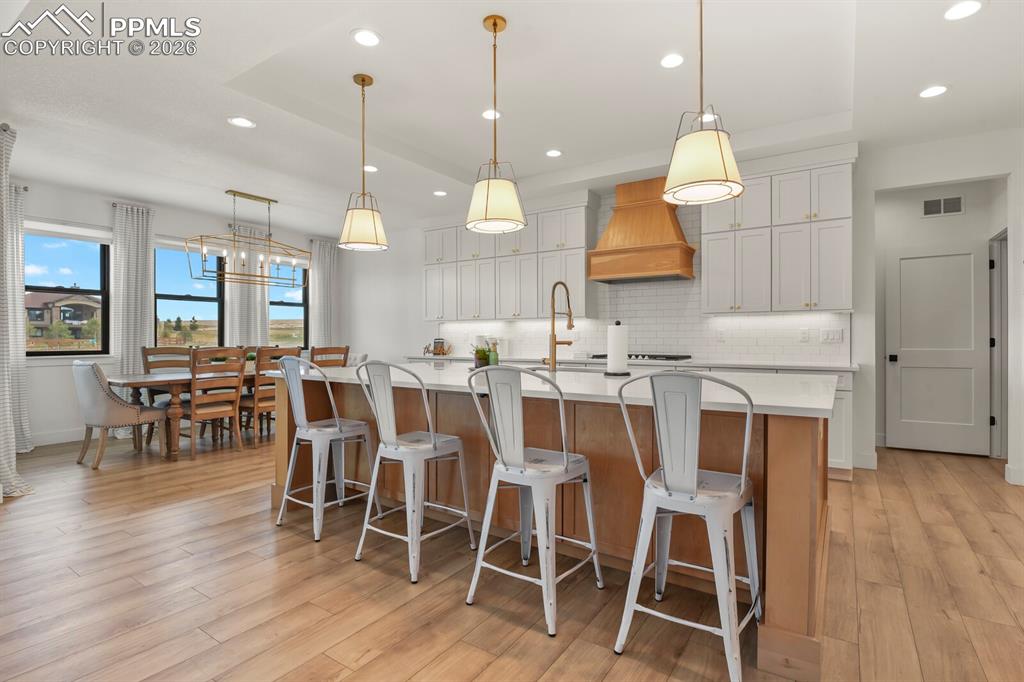 Image 9 of 47: Two tone kitchen featuring a kitchen bar, a large island, light wood-type f
