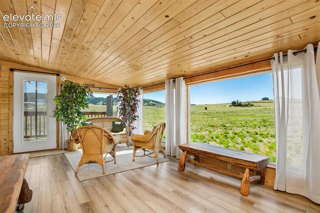 Image 12 of 29: Sunroom featuring expansive windows, wood-finish flooring, and a natural wo