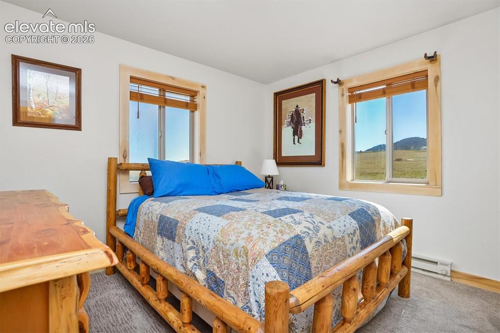 Image 13 of 29: Bedroom featuring rustic wood-finish window trim, a large window, and light
