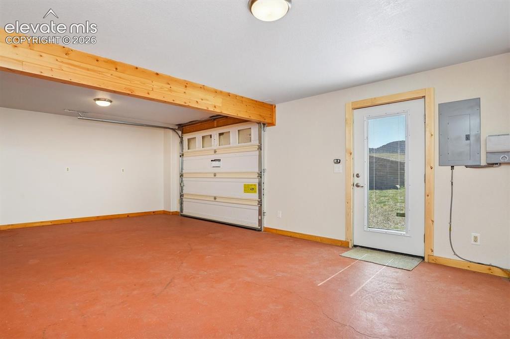 Image 18 of 29: Spacious garage featuring a roll-up door, a painted concrete floor, and an 