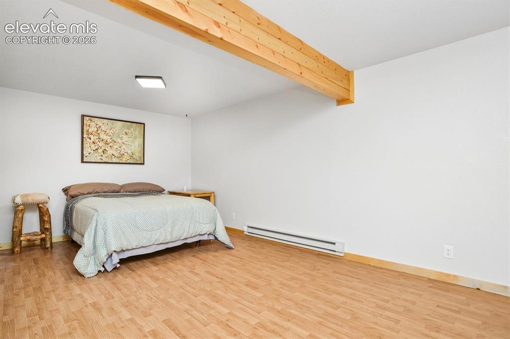 Image 20 of 29: Spacious room featuring wood-finish flooring, white walls, and an exposed w