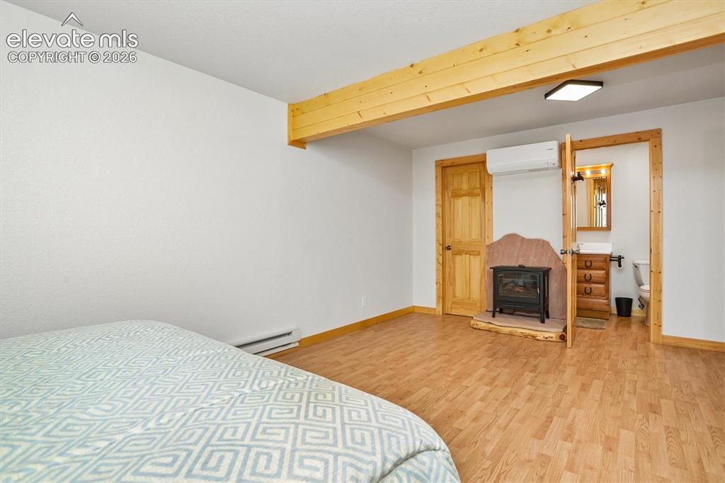 Image 21 of 29: Spacious room featuring wood-finish flooring, exposed wood beam, a freestan