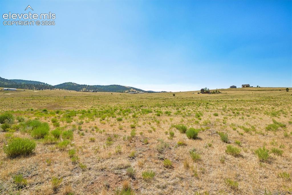 Image 28 of 29: Expansive land parcel featuring natural grasses and distant rolling hills