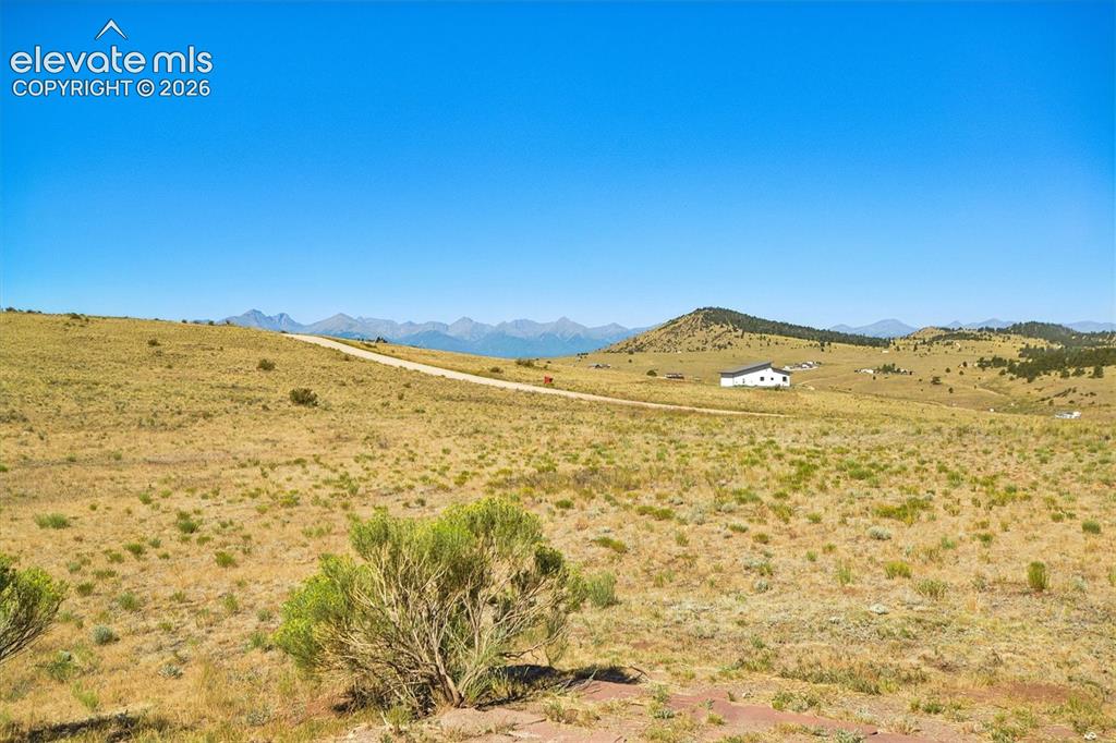 Image 29 of 29: Expansive open terrain with a dirt road, distant mountains, and a white res