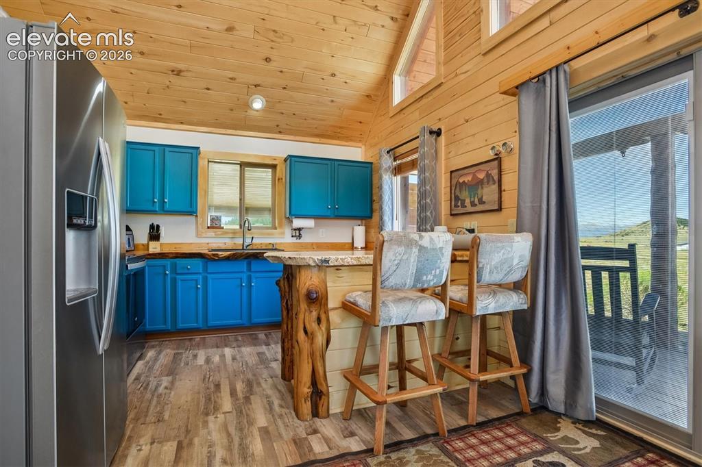 Image 7 of 29: Kitchen featuring wood-finish flooring, vibrant blue cabinetry, stainless s