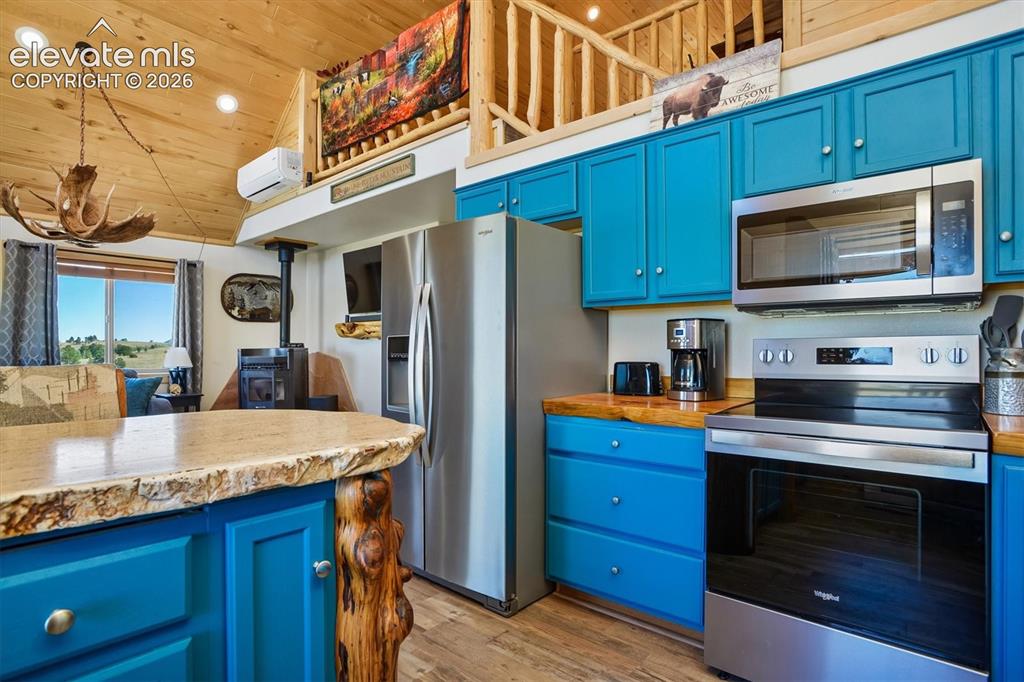 Image 9 of 29: Kitchen featuring teal cabinetry, wood-finish countertops, and stainless st