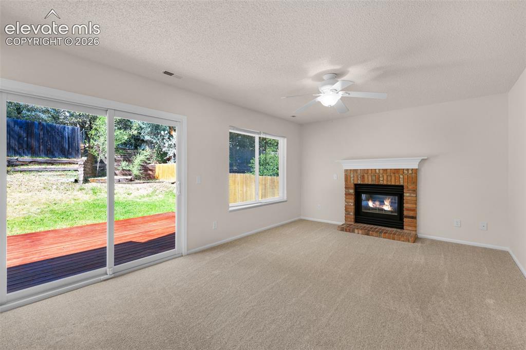 Image 13 of 44: Family room with access to deck and cozy fireplace.