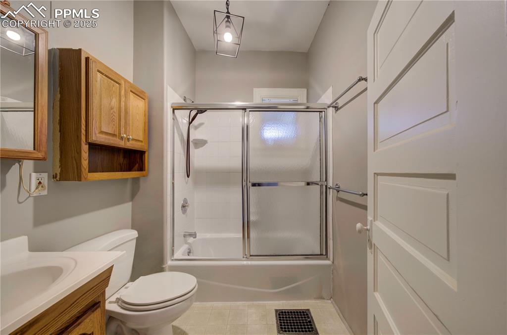 Image 15 of 19: Full bathroom with combined bath / shower with glass door, vanity, and ligh