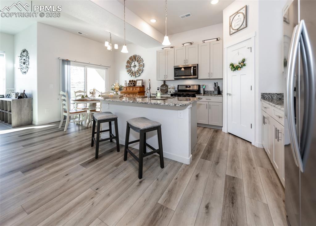 Image 12 of 49: Kitchen with stainless steel appliances, light stone countertops, a center