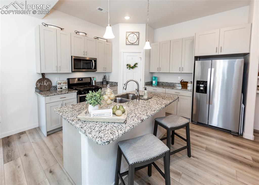 Image 14 of 49: Kitchen with stainless steel appliances, a kitchen breakfast bar, light sto