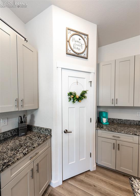 Image 15 of 49: Kitchen with dark stone counters and light wood-style floors