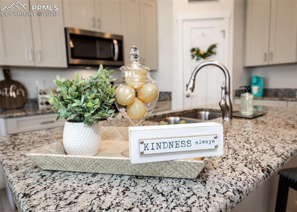 Image 16 of 49: Kitchen view of light stone countertops, stainless steel microwave, and a b
