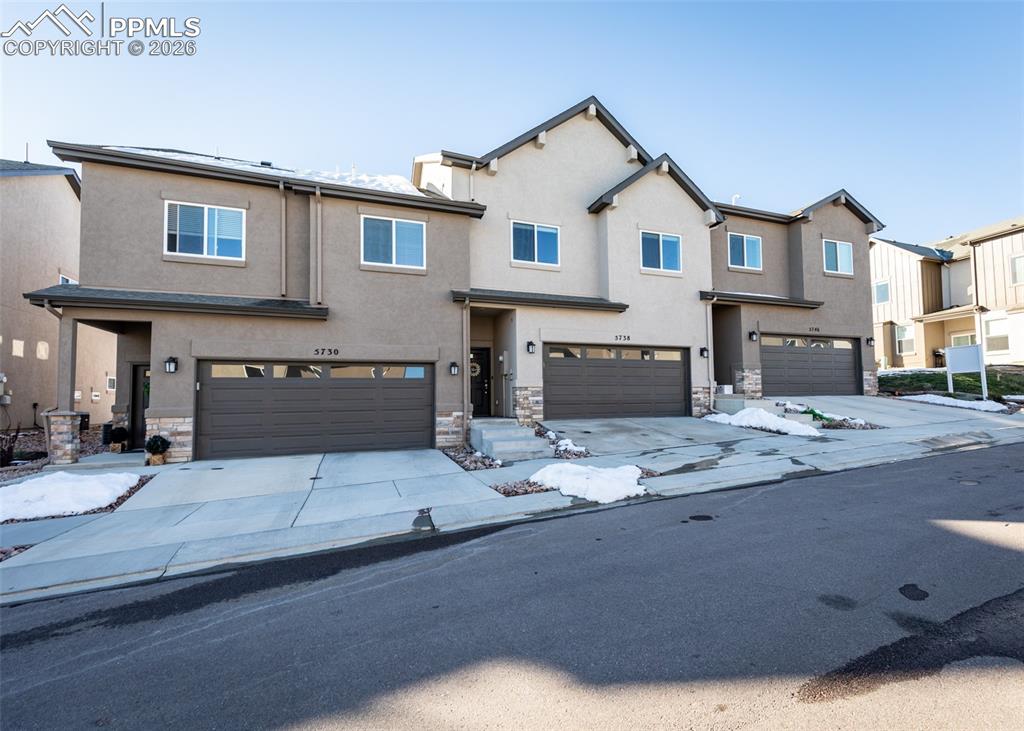 Image 2 of 49: Traditional-style house featuring stone siding, an attached garage, stucco