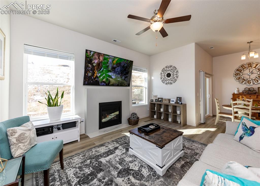 Image 20 of 49: Living area with a ceiling fan, wood finished floors, and a fireplace with