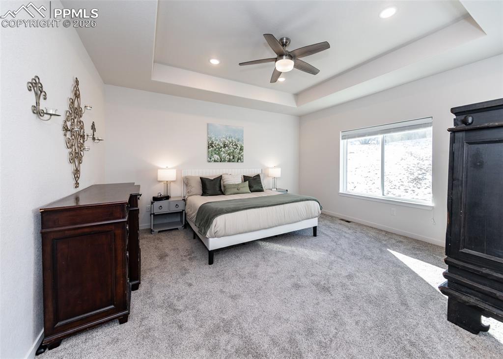 Image 26 of 49: Bedroom with ceiling fan, light carpet, recessed lighting, and a tray ceili