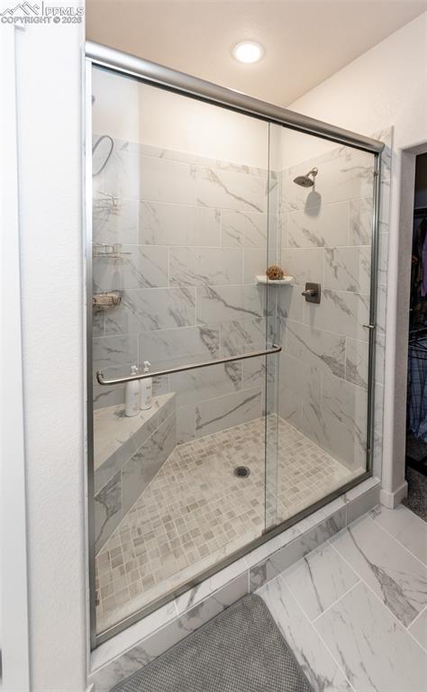 Image 31 of 49: Full bath featuring light marble finish flooring, a shower stall, a spaciou