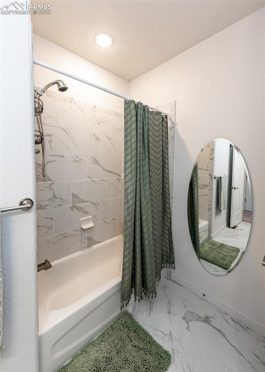 Image 38 of 49: Bathroom with shower / bath combination with curtain and light marble finis