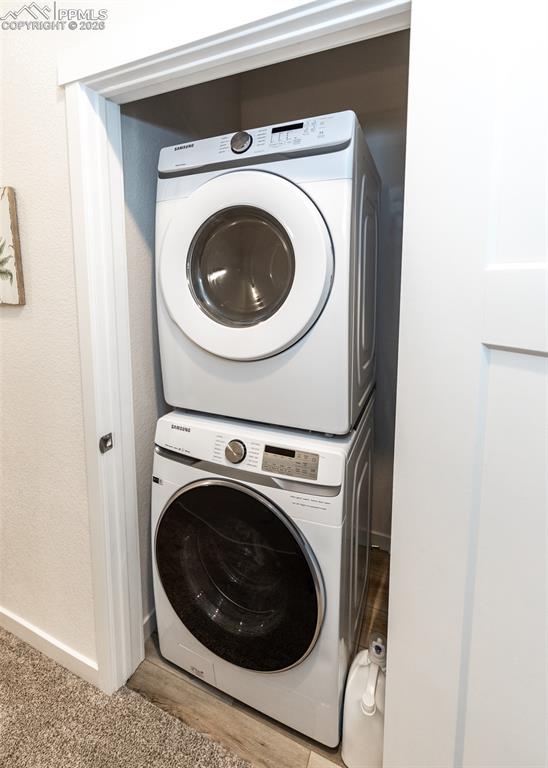Image 41 of 49: Laundry area featuring stacked washer / drying machine and baseboards