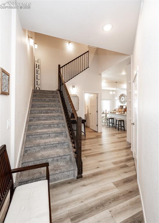 Image 5 of 49: Stairs featuring wood finished floors, a high ceiling, and recessed lightin