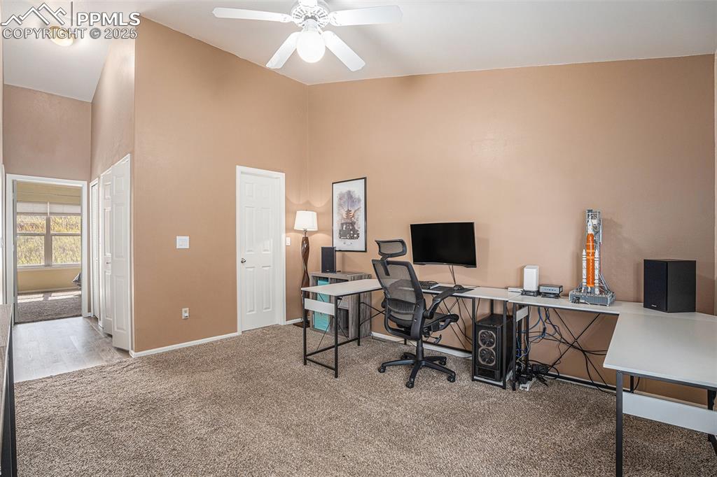 Image 15 of 22: Office/loft/multiple use area with light colored carpet, ceiling fan, and v