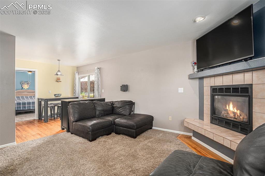 Image 4 of 22: Living room featuring newly installed light colored carpet, a tile fireplac