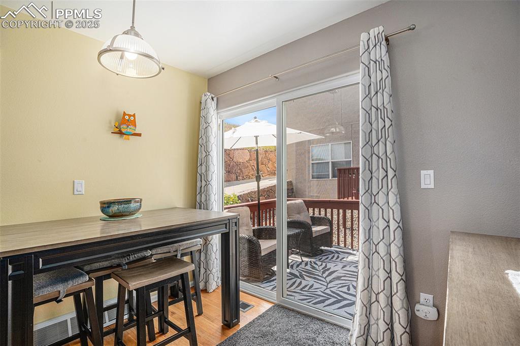 Image 7 of 22: Dining area with hardwood floors and slider to cozy deck